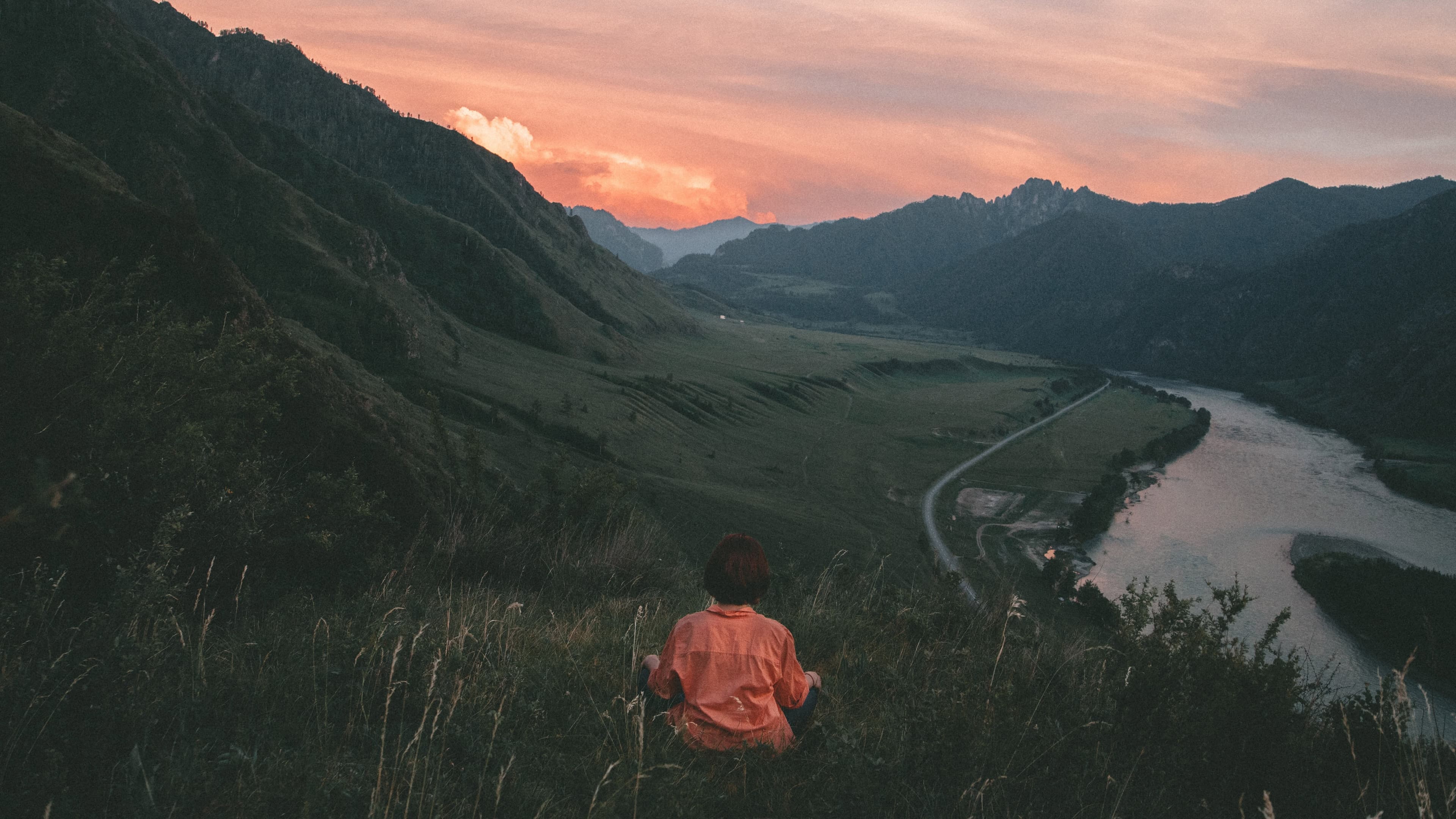 woman meditates in front of a sunset landscape